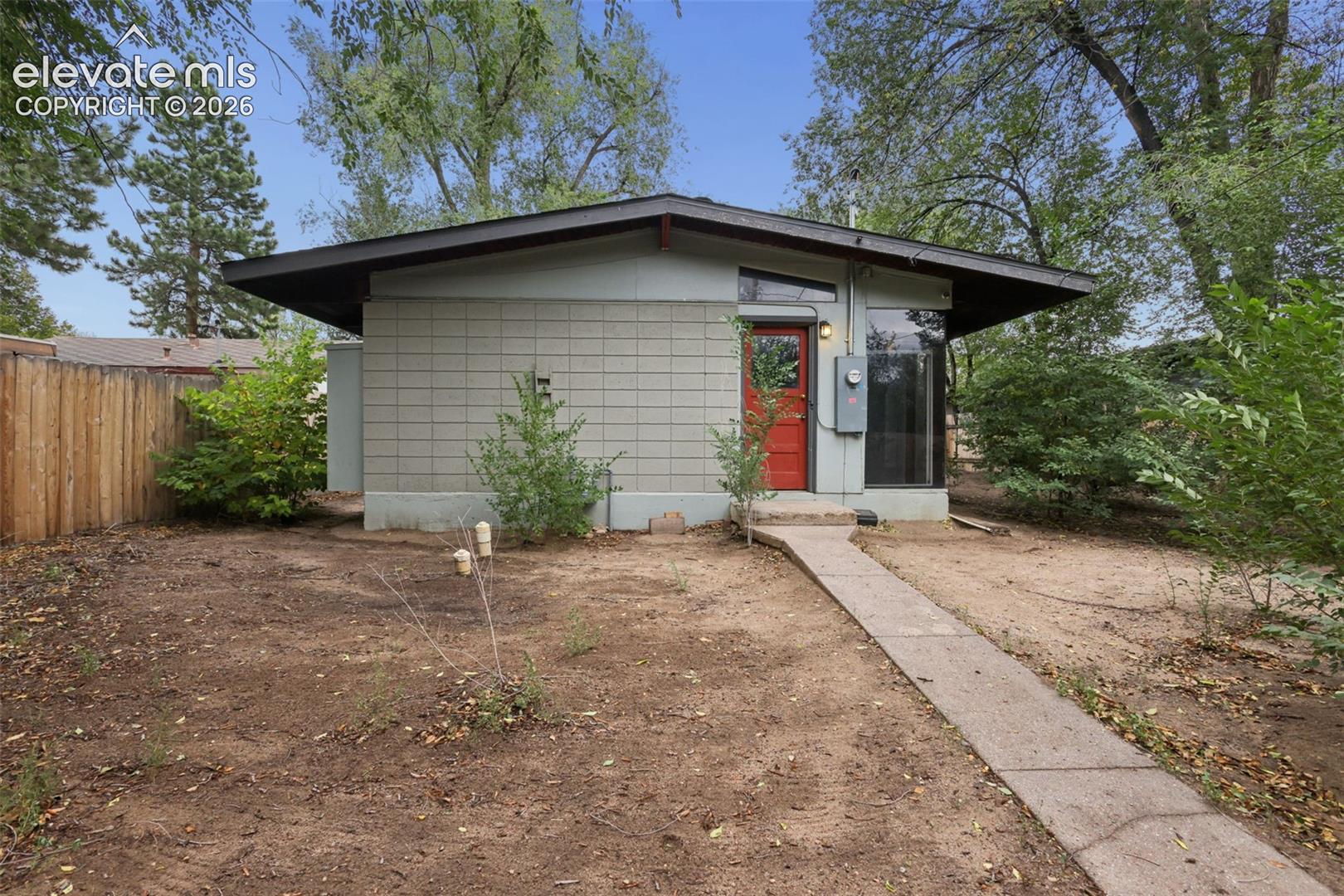 Mid-century modern architecture with a low-slope roofline, a striking red entry door, and expansive windows