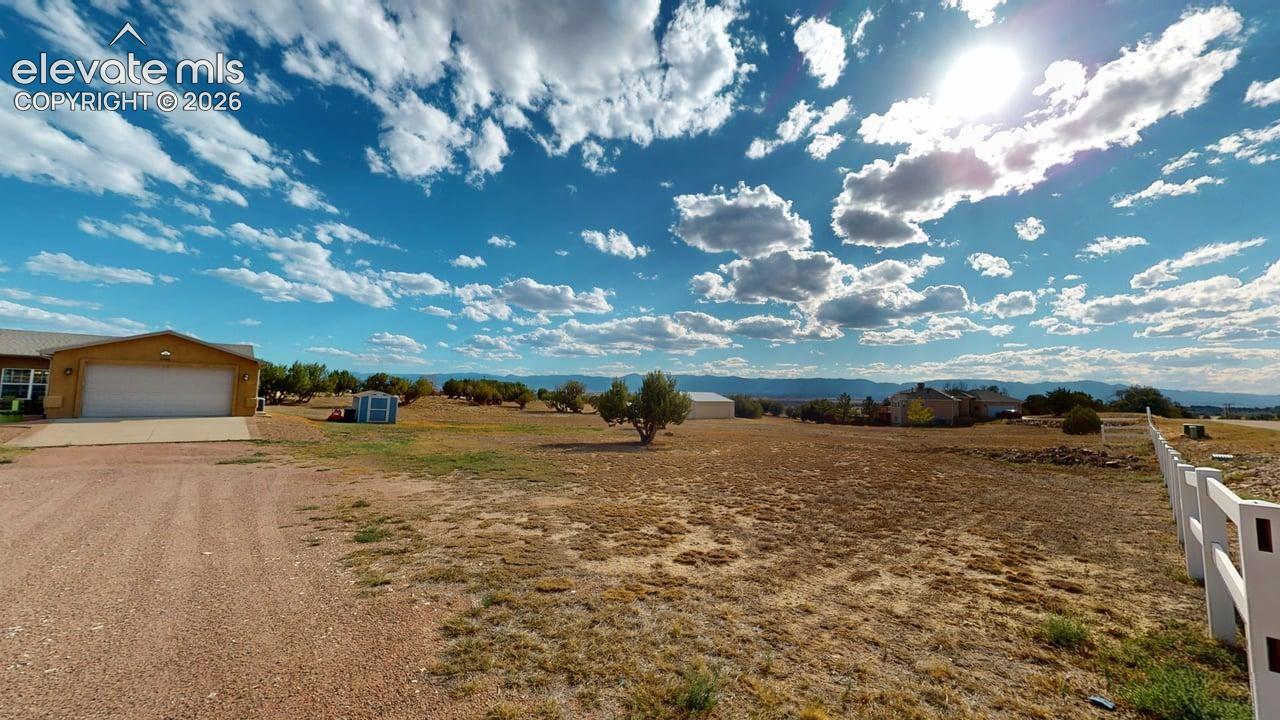 Expansive property with a gravel driveway, attached garage, and a white picket fence bordering the perimeter