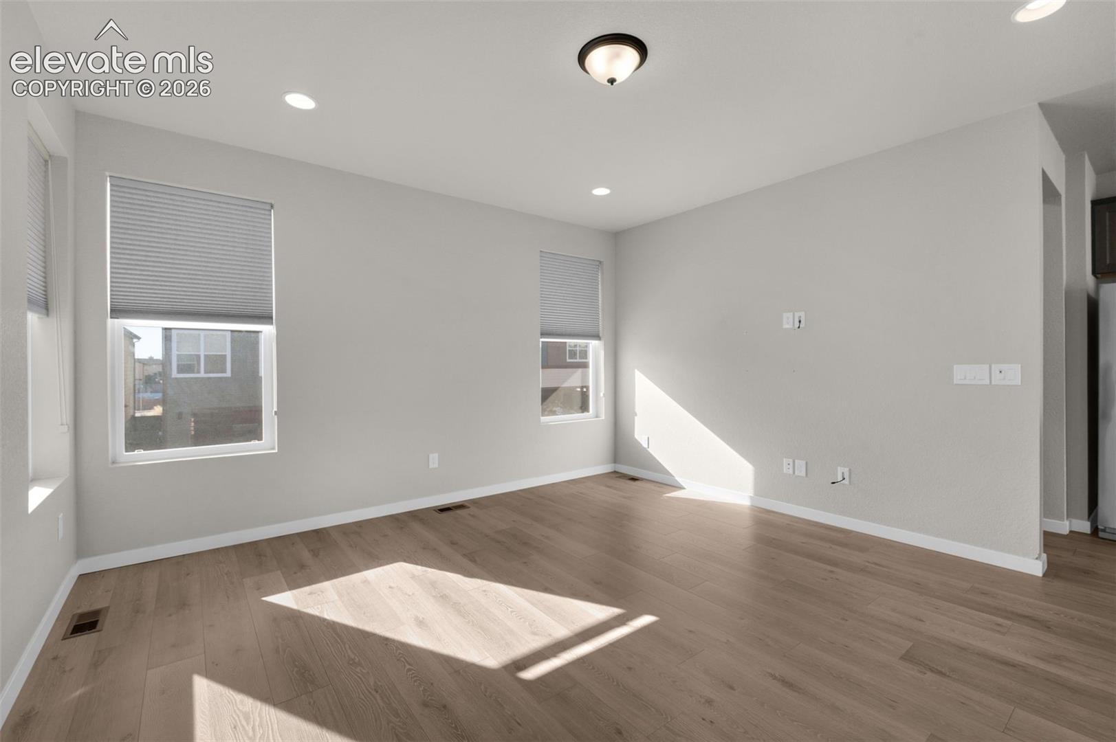 Recessed lighting, wood-finish flooring, multiple windows with blinds, neutral wall tones, and a semi-flush mount ceiling fixture