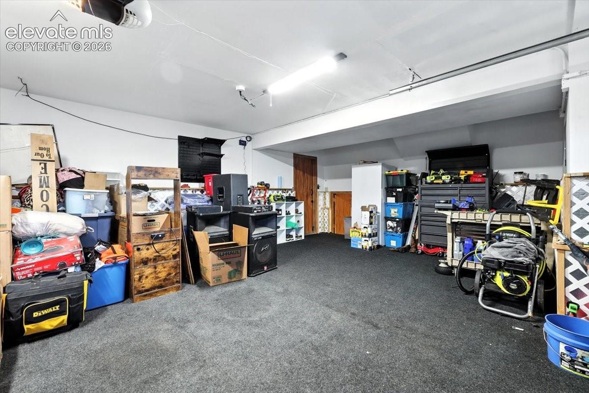 Enclosed garage featuring dark floor surfacing and overhead industrial lighting
