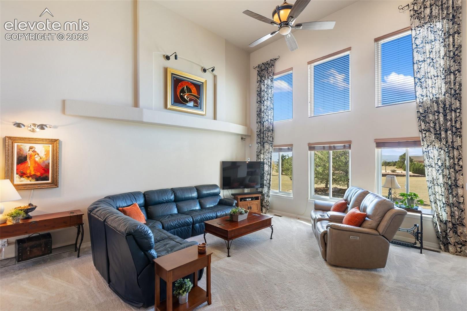 Living area featuring vaulted ceilings, floor-to-ceiling windows, a built-in recessed wall niche, and a multi-blade ceiling fan