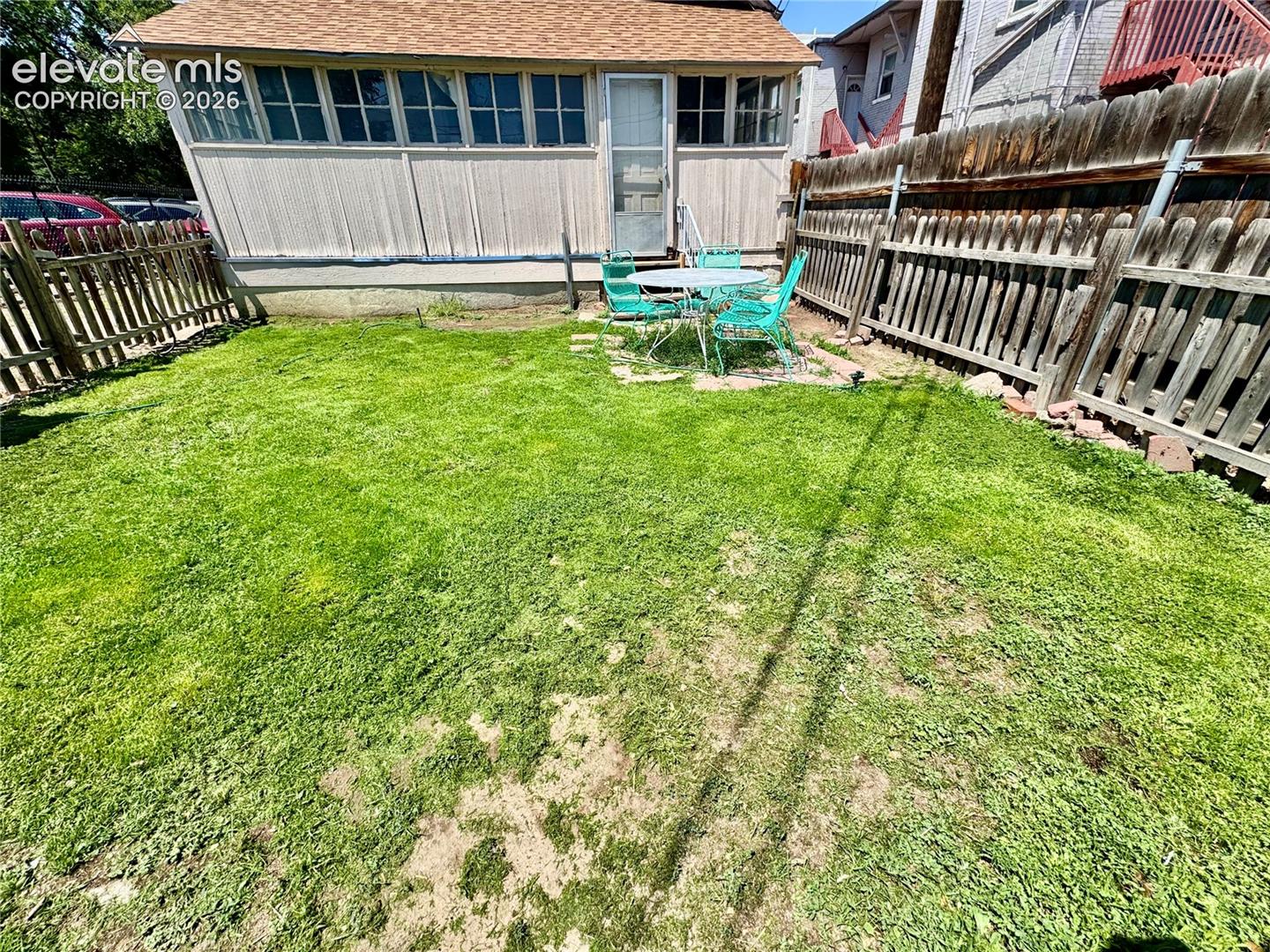 Enclosed backyard with a wooden privacy fence and a sunroom with multiple windows