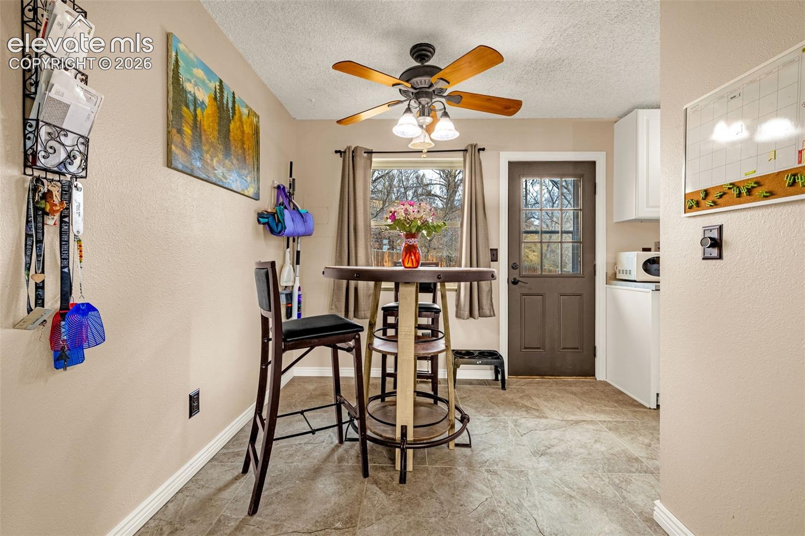 Textured tile flooring, ceiling fan with integrated lighting, and a multi-pane glass entry door