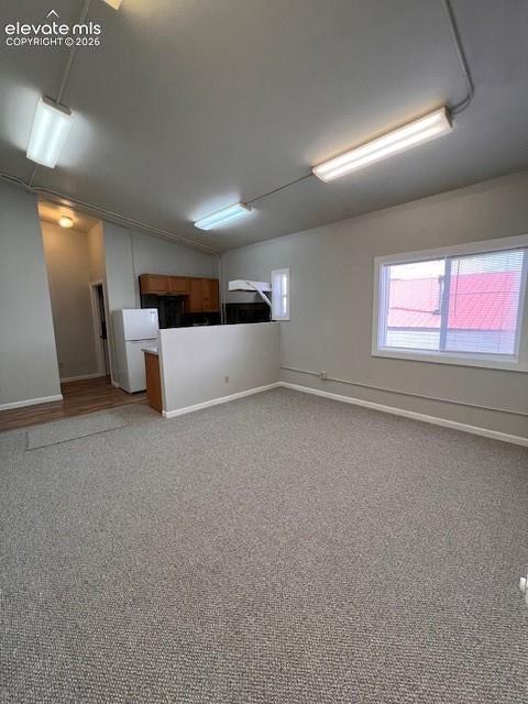 Open-concept room featuring wall-to-wall carpeting, linear fluorescent lighting fixtures, and a pass-through wall separator