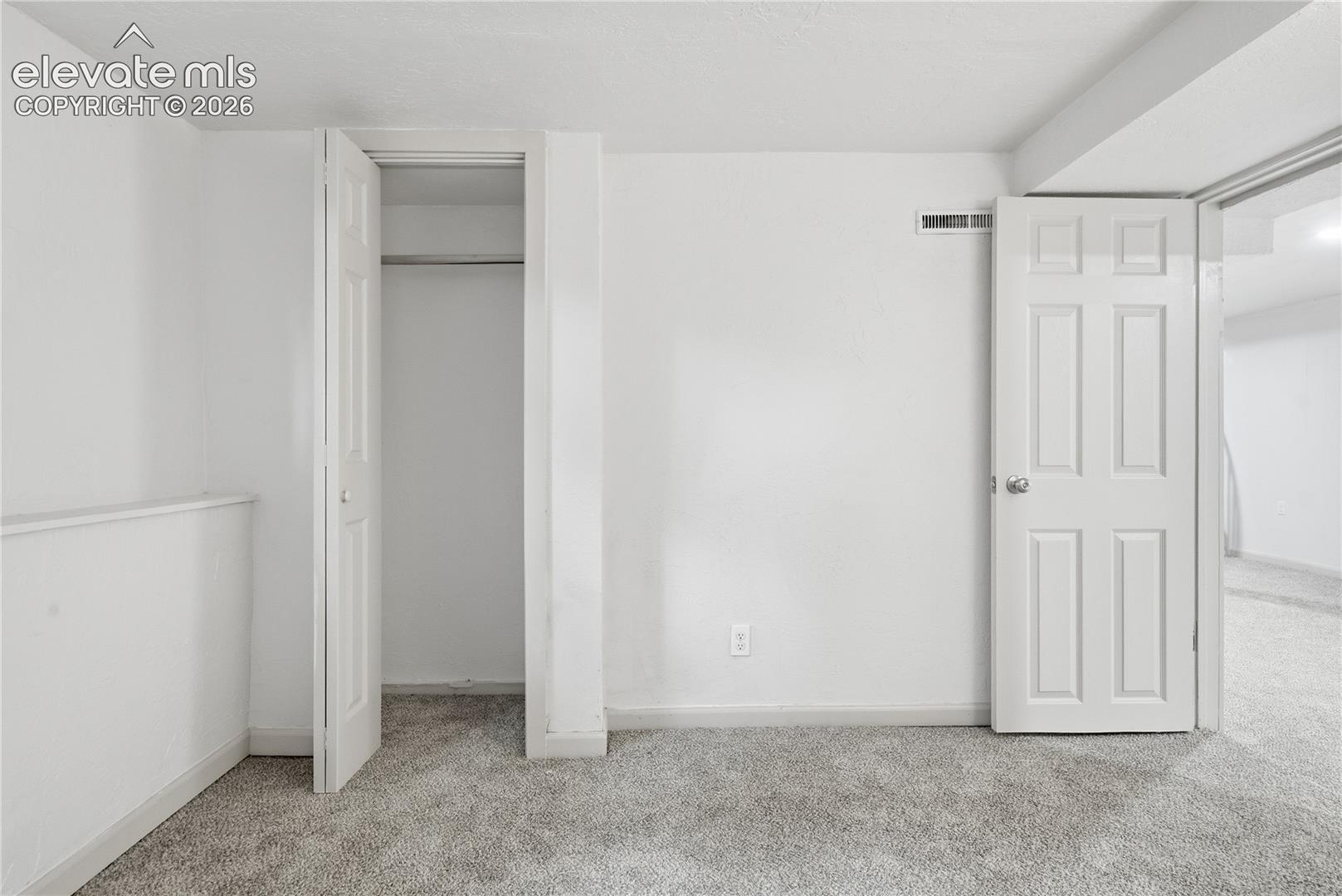 Interior space featuring neutral-toned carpeting, six-panel interior doors, and a built-in closet with integrated shelving