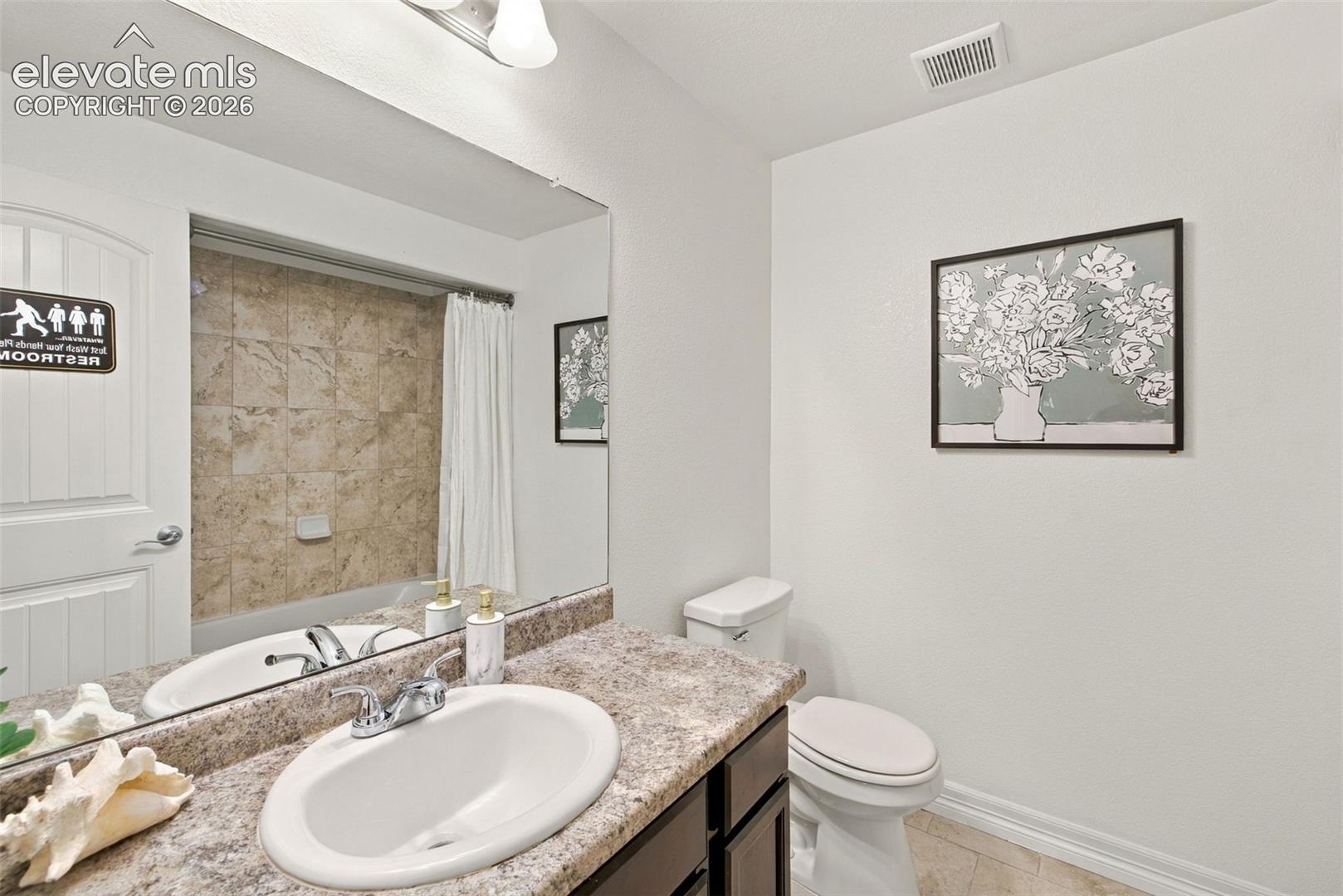 Bathroom featuring a vanity with an integrated oval sink and stone-finish countertop, full-width mirror, brushed-nickel faucet, and a tiled shower surround