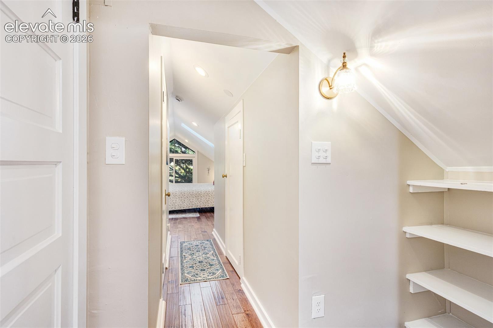Hallway with wood-finish flooring, recessed lighting, and a wall-mounted sconce
