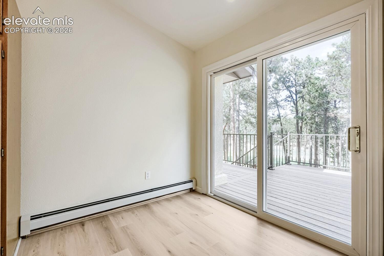 Sliding glass door opening to an outdoor deck with metal railings, light wood-finish flooring, and recessed ceiling lighting