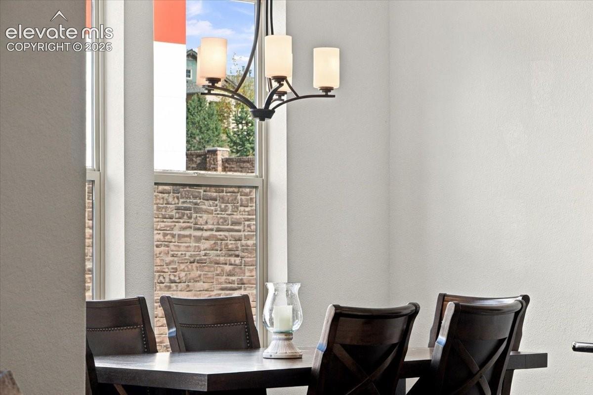 Multi-light metal chandelier with frosted glass shades, tall vertical windows, and textured exterior stone masonry