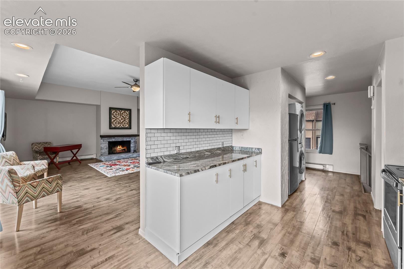 Kitchen featuring white cabinetry, stone-finish countertops, subway tile backsplash, and wood-finish flooring