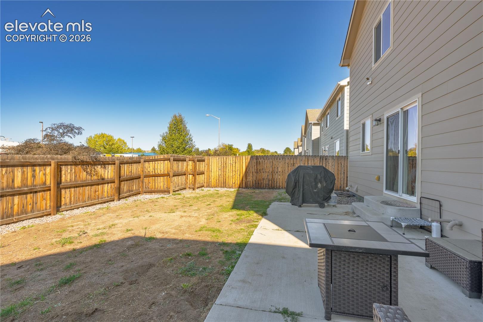 Rear exterior space featuring a concrete patio, wood-style horizontal lap siding, and a wooden privacy fence