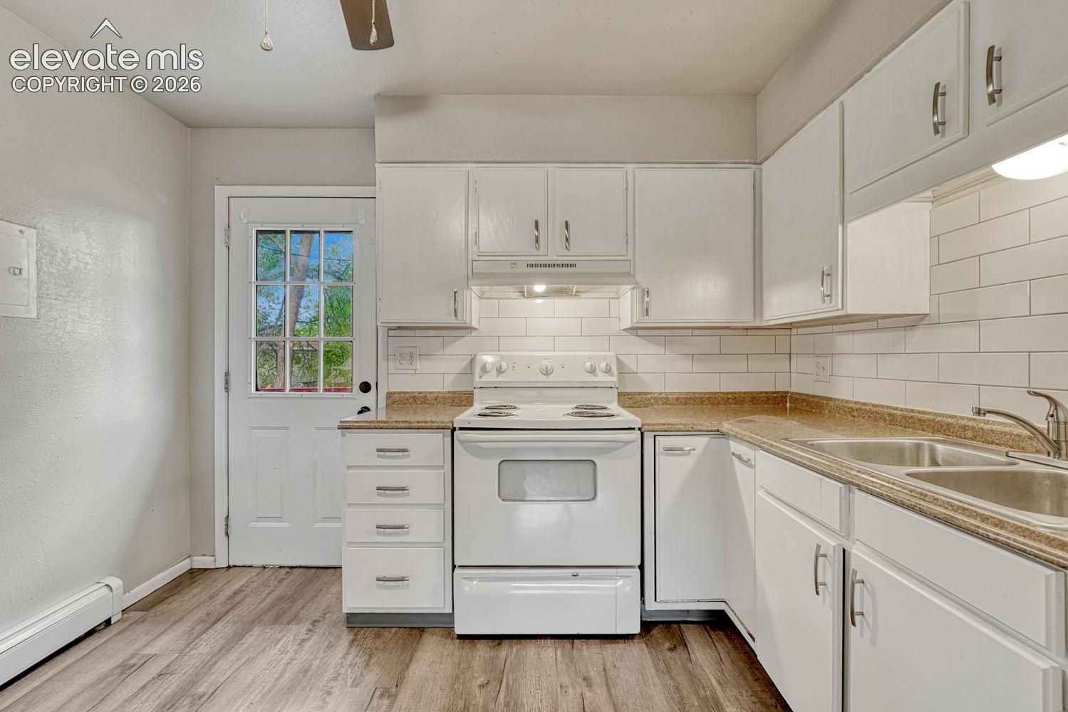 Kitchen featuring white cabinetry, white subway tile backsplash, wood-finish flooring, and a glass-paneled exterior door
