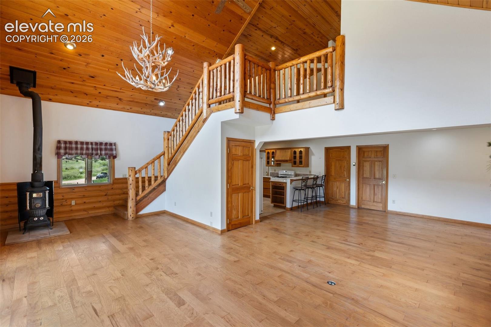 Warm and inviting, the family room showcases a log staircase, classic pot-bellied wood stove, and antler chandelier, with open living space that leads directly to a patio where you can enjoy the stream and watch horses in the pasture.