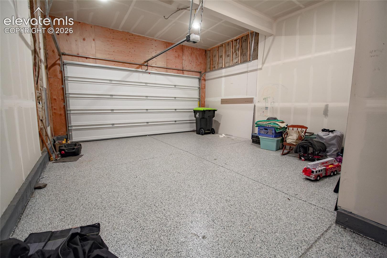 Attached garage featuring an epoxy-coated concrete floor and an automatic roll-up door