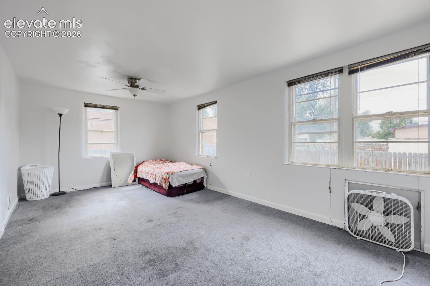 Ceiling fan, multiple windows, and light gray carpeting