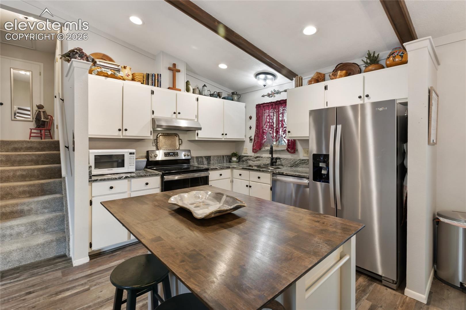 Kitchen featuring white cabinetry, wood-finish flooring, stainless steel appliances, a center island with a wood-finish countertop, and recessed lighting