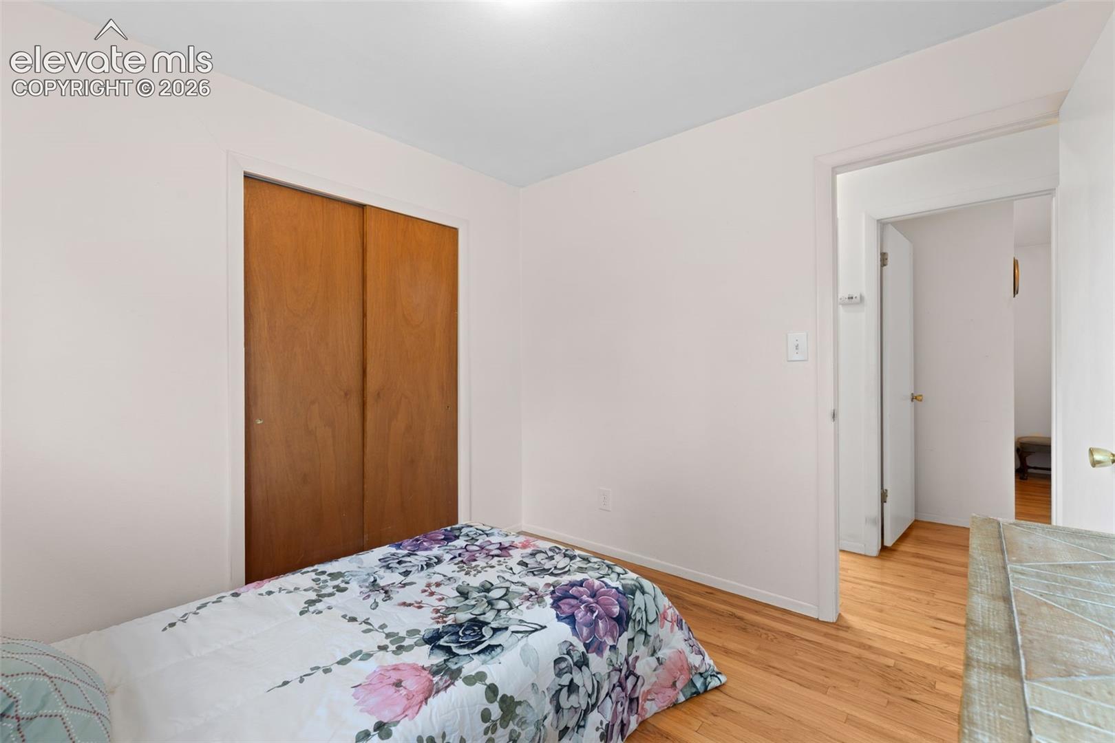Hardwood flooring, sliding wood-finish closet doors, white walls, and white ceiling