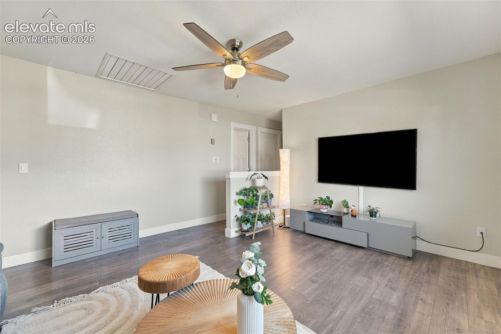 Wood-finish flooring with a ceiling fan light fixture and a wall-mounted display