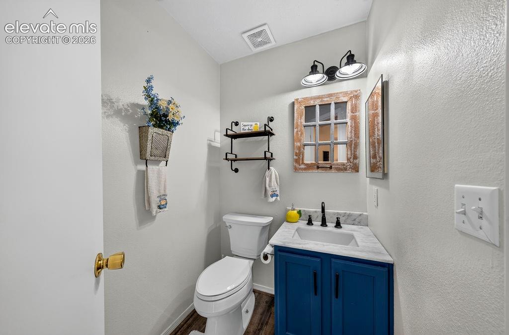 Powder room featuring a blue vanity, a rectangular sink with a matte black faucet, and a wall-mounted light fixture