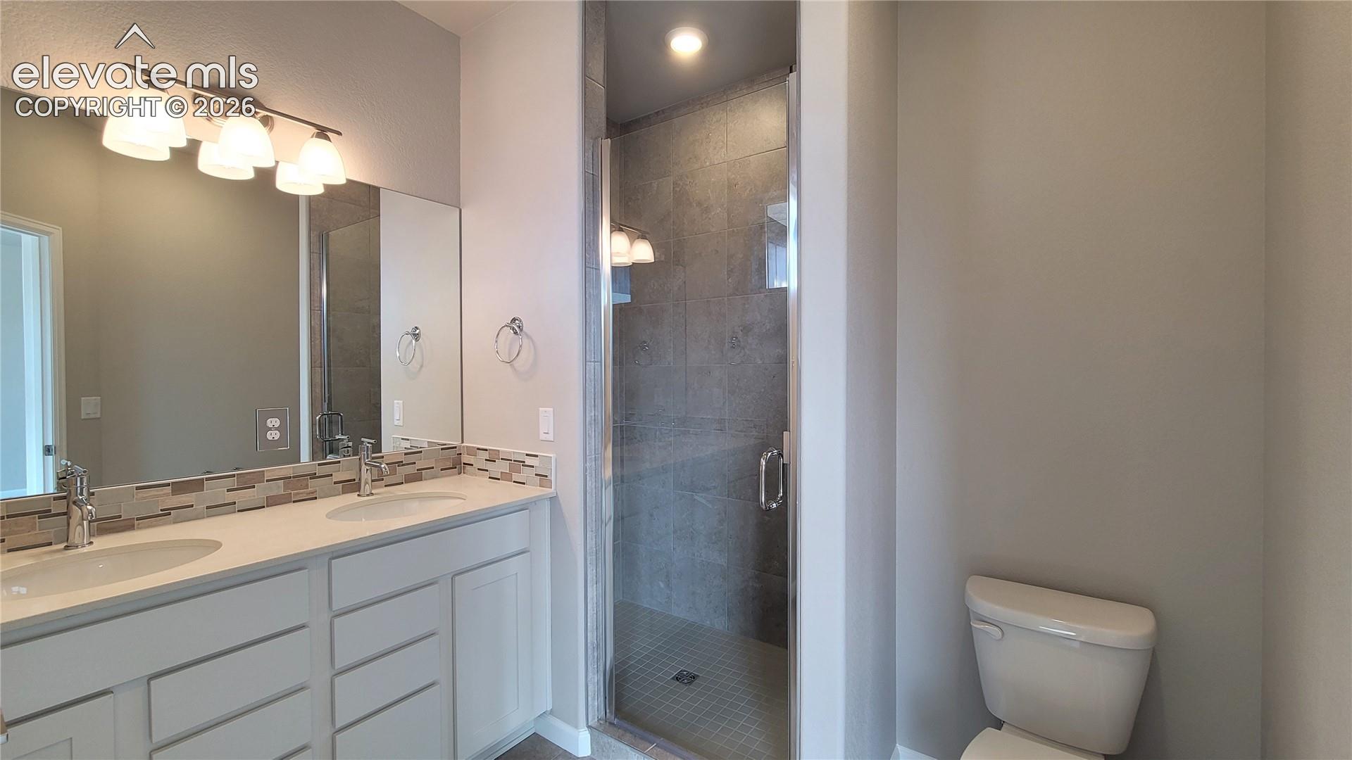 Primary Bathroom with quartz countertop with double vanity, shower, and tile surrounds! 