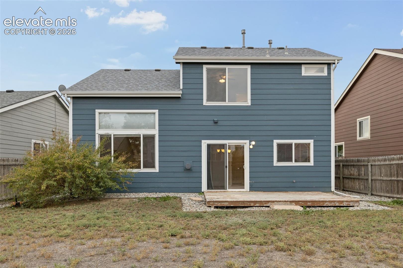 Two-story exterior featuring blue horizontal lap siding, a rear wood deck, and multiple windows with white trim