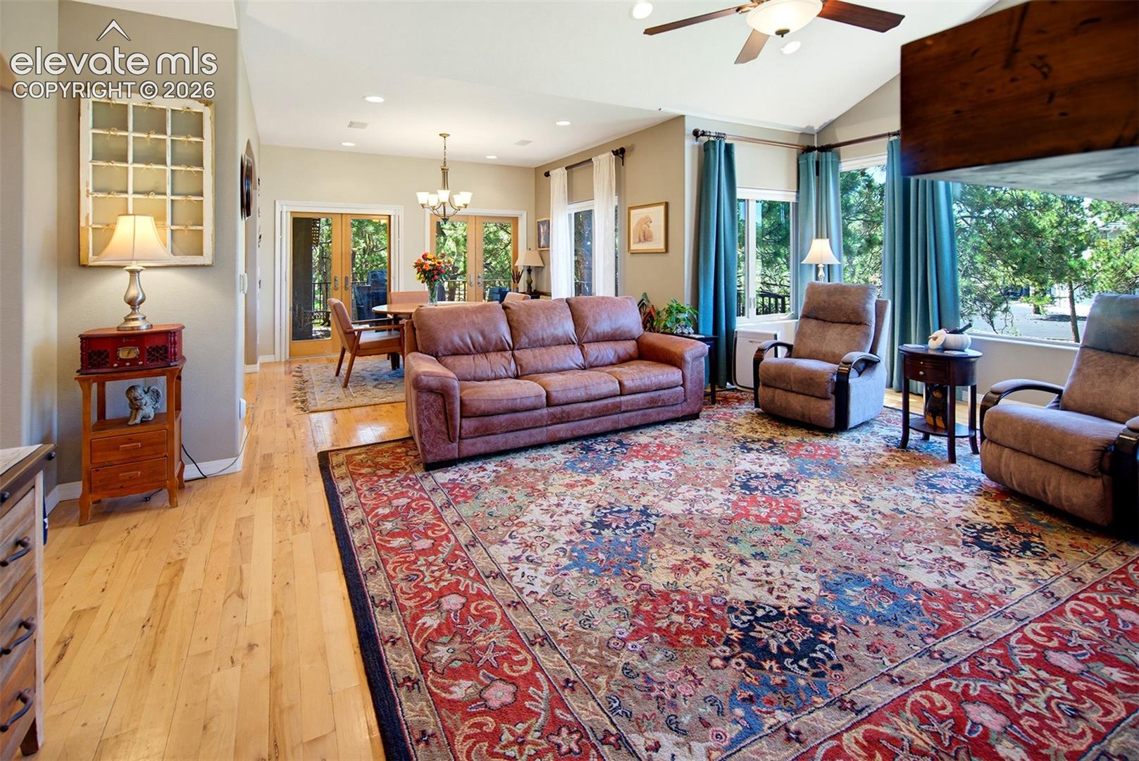 Vaulted ceiling, ceiling fan, light wood-finish flooring, recessed lighting, and double French doors leading to a covered deck