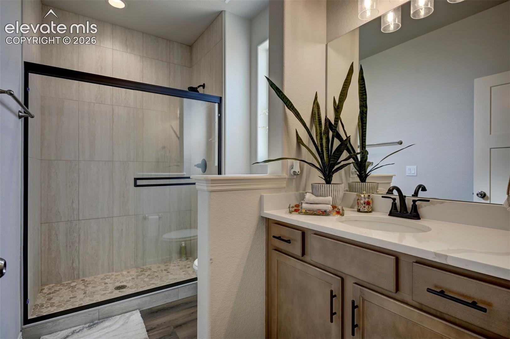 Contemporary bathroom featuring a walk-in shower with vertical tile and pebble flooring