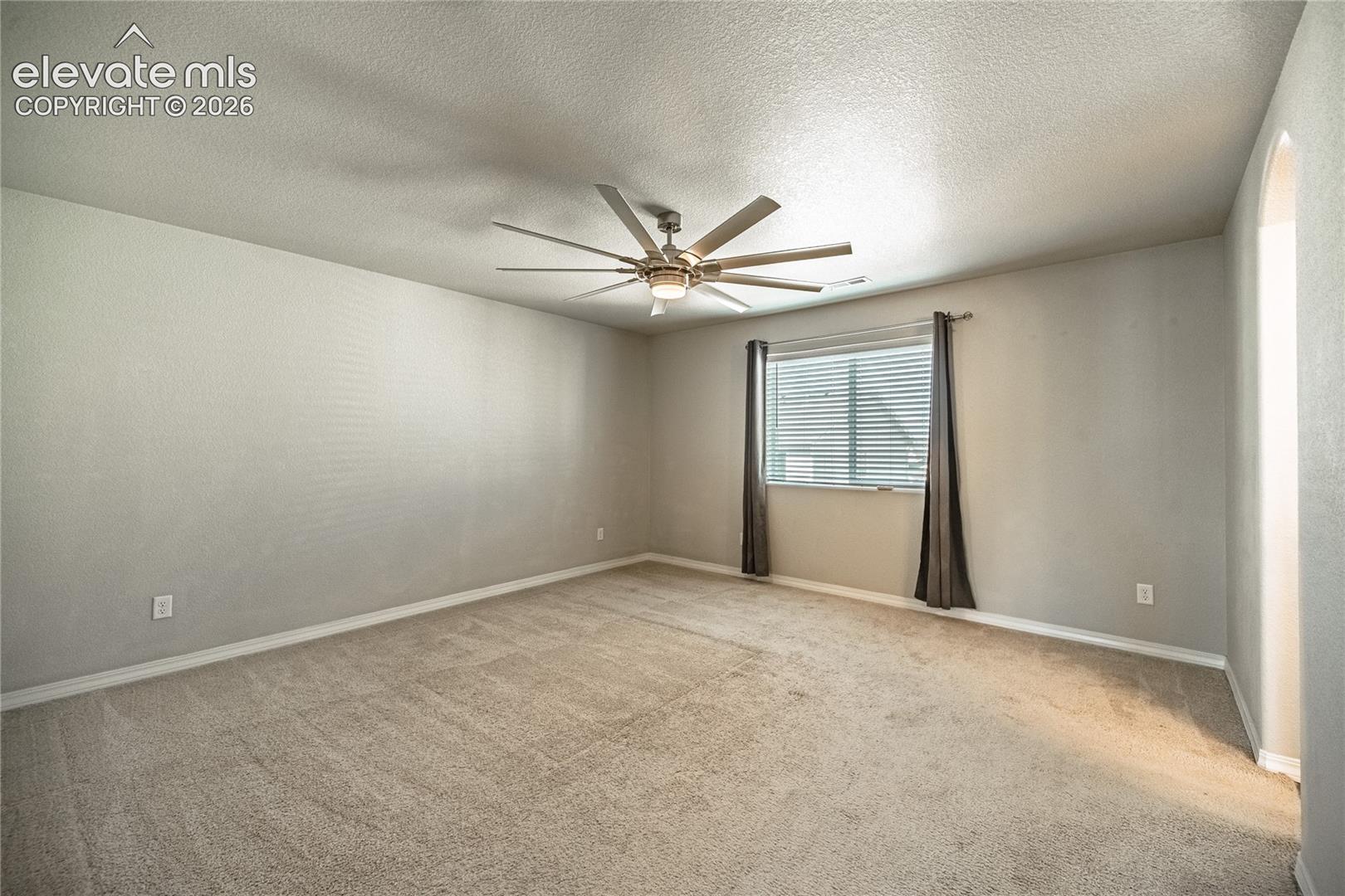Carpeted flooring, window with blinds, ceiling fan with integrated lighting, and neutral wall tones