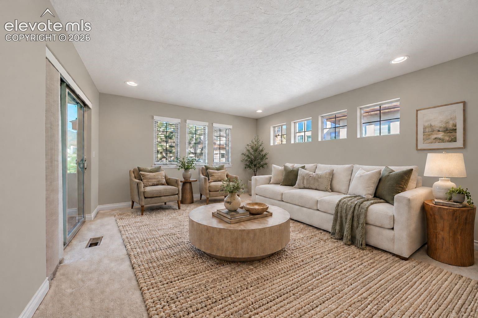 Living area featuring neutral-toned walls, recessed lighting, multiple oversized windows, and sliding glass door access