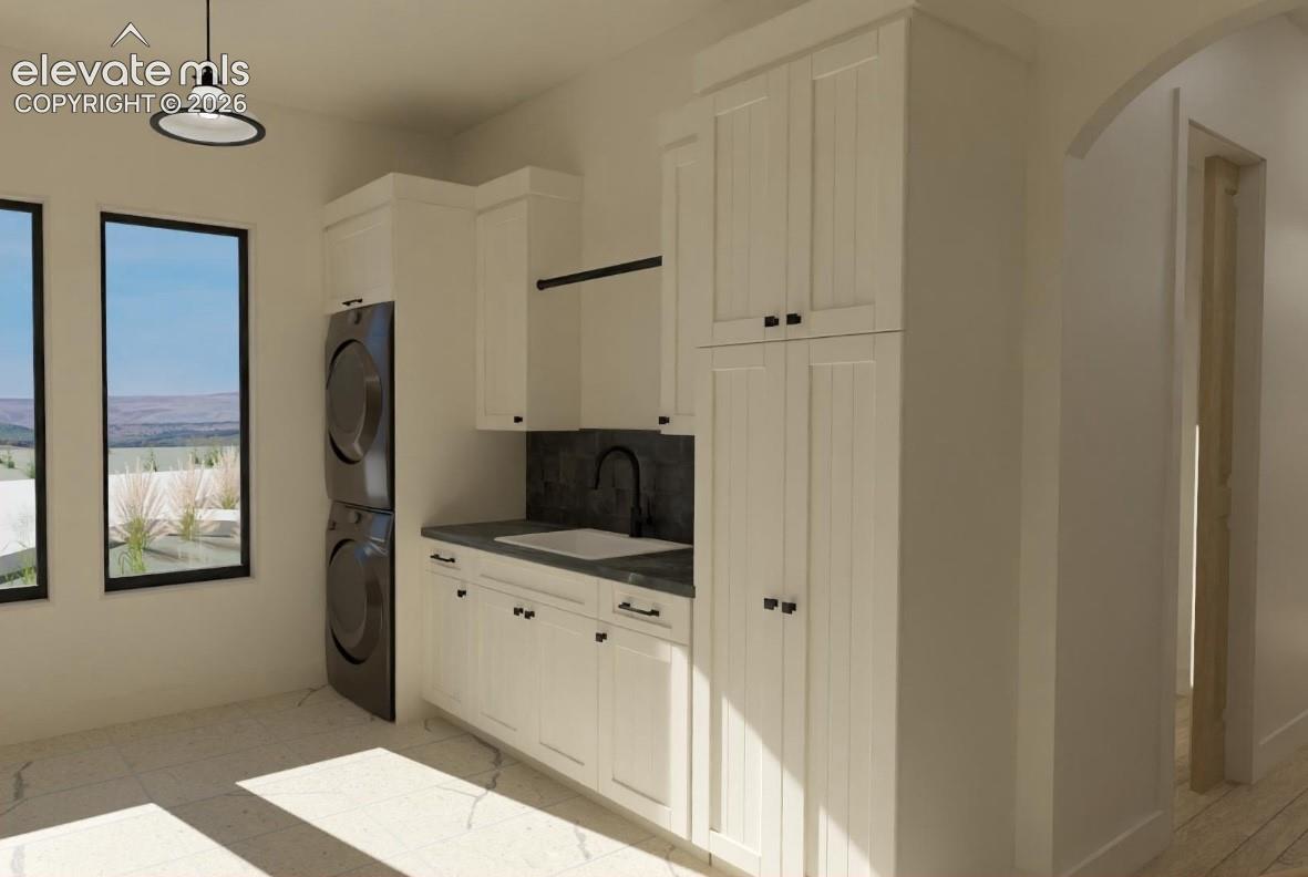 Laundry area featuring white cabinetry, integrated sink with matte black faucet, and two large windows
