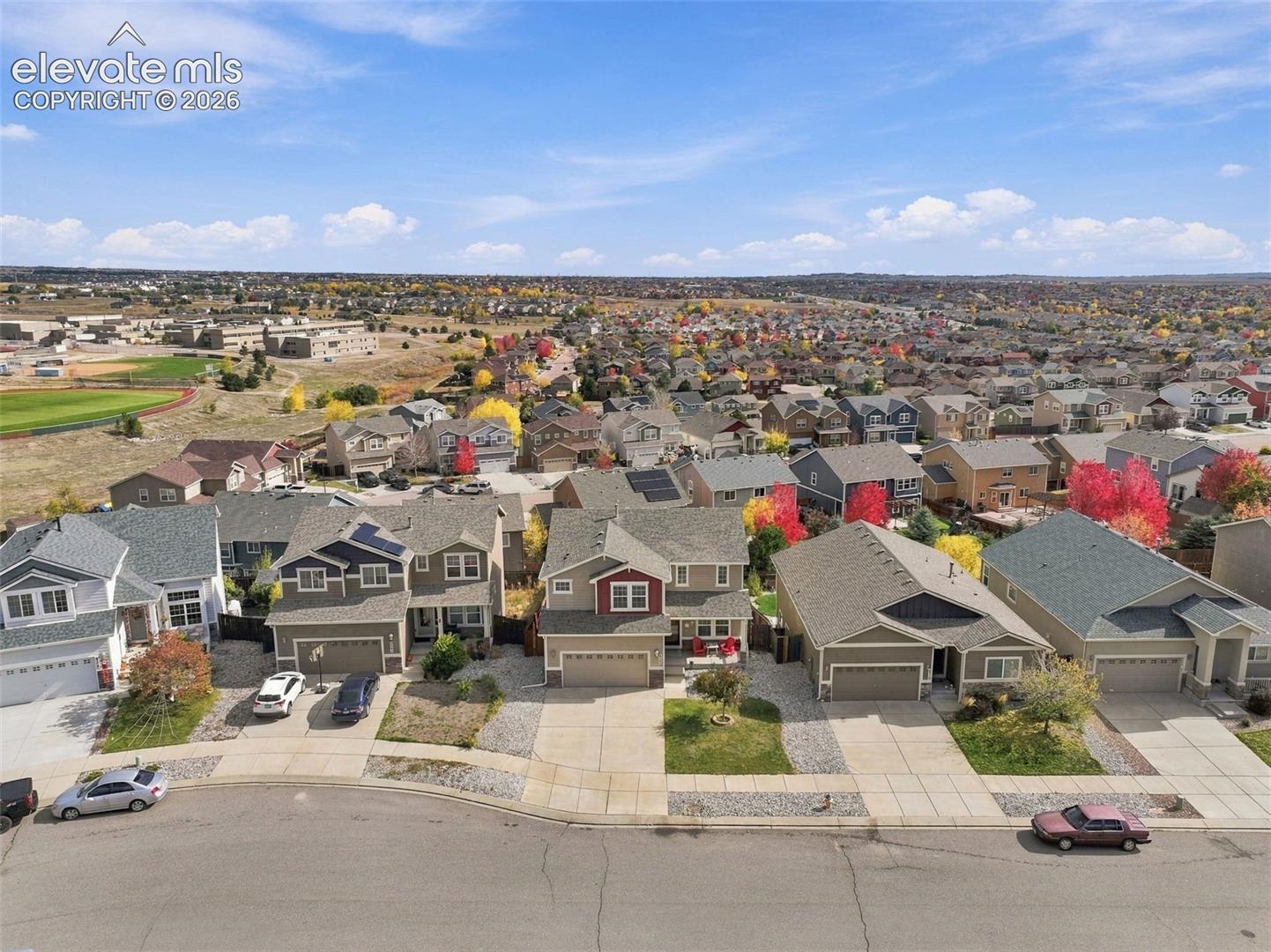 Aerial perspective of a suburban neighborhood featuring multi-story dwellings, attached garages, concrete driveways, and established landscaping