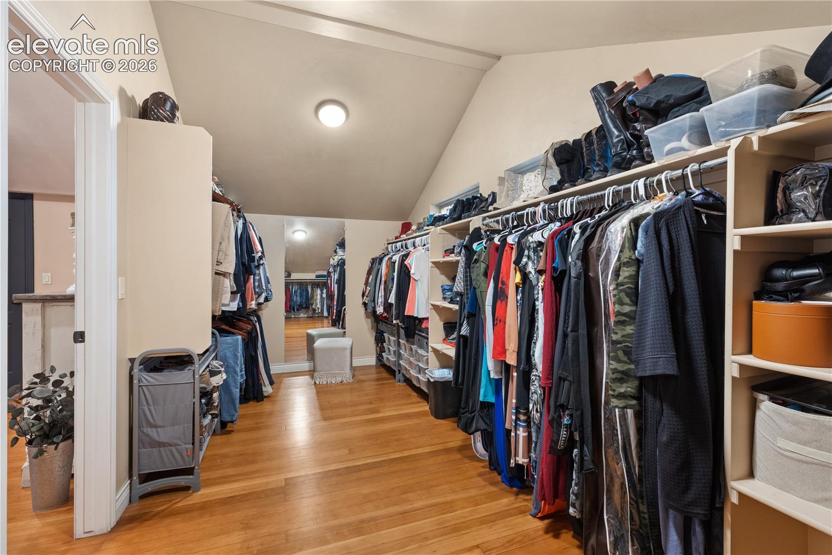 Spacious closet featuring wood-finish flooring, sloped ceiling, recessed lighting, built-in shelving, and hanging storage