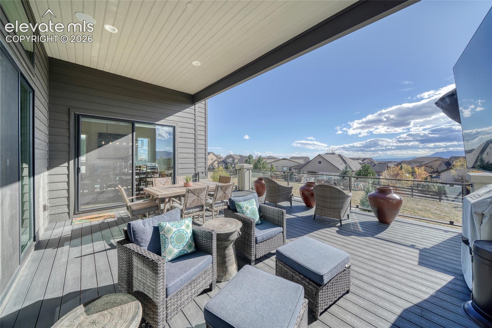 Covered deck featuring composite decking, recessed lighting, and a glass panel railing