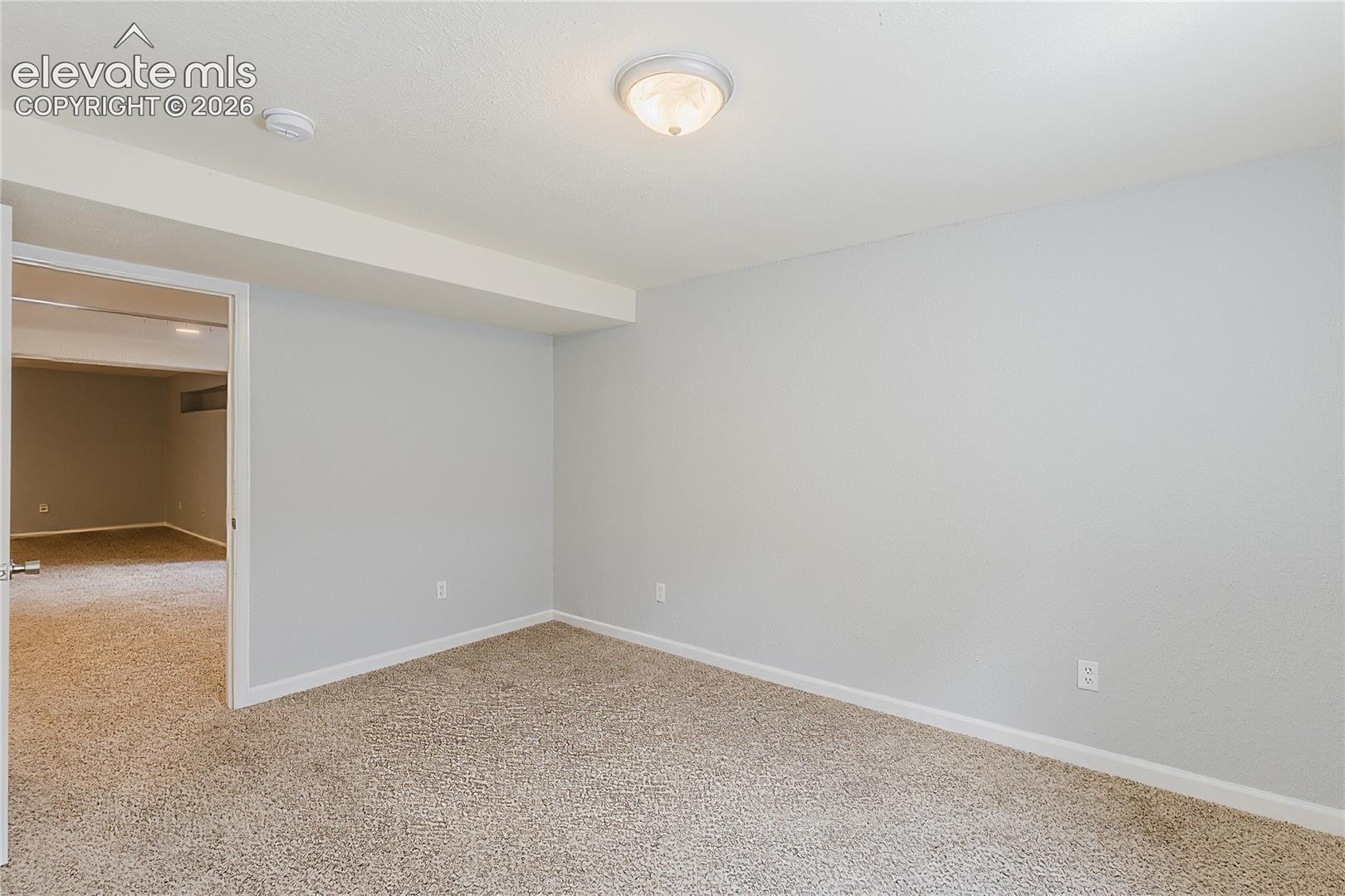 Neutral tone wall paint with matching trim, textured carpet flooring, and a flush-mount ceiling light