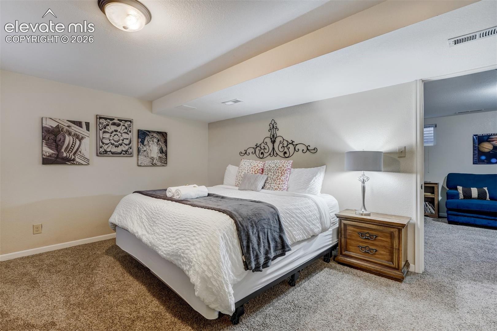 Carpeted flooring throughout, recessed ceiling light fixture, and a decorative wall-mounted headboard