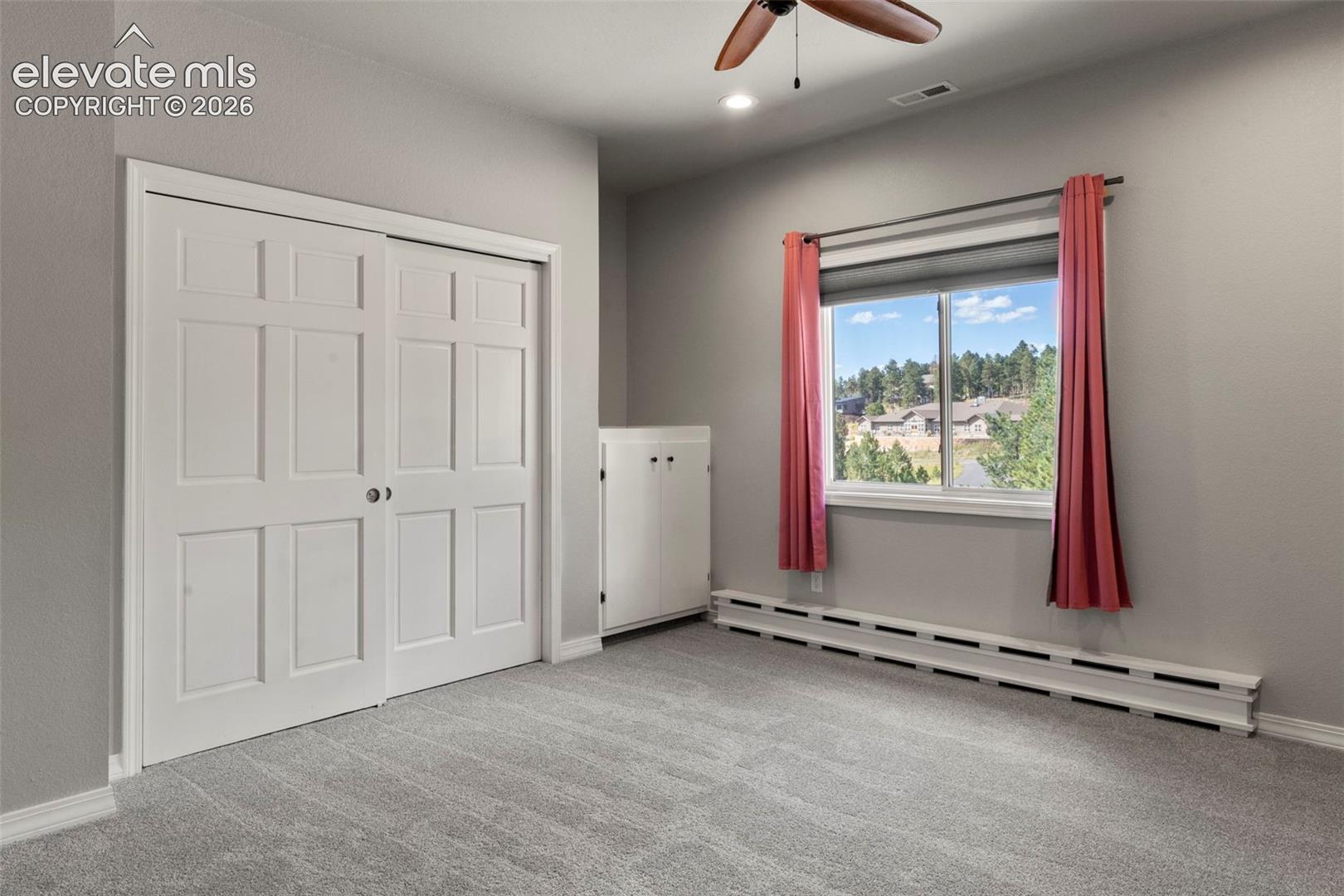 Unfurnished bedroom featuring a baseboard radiator, light carpet, ceiling fan, a closet, and recessed lighting