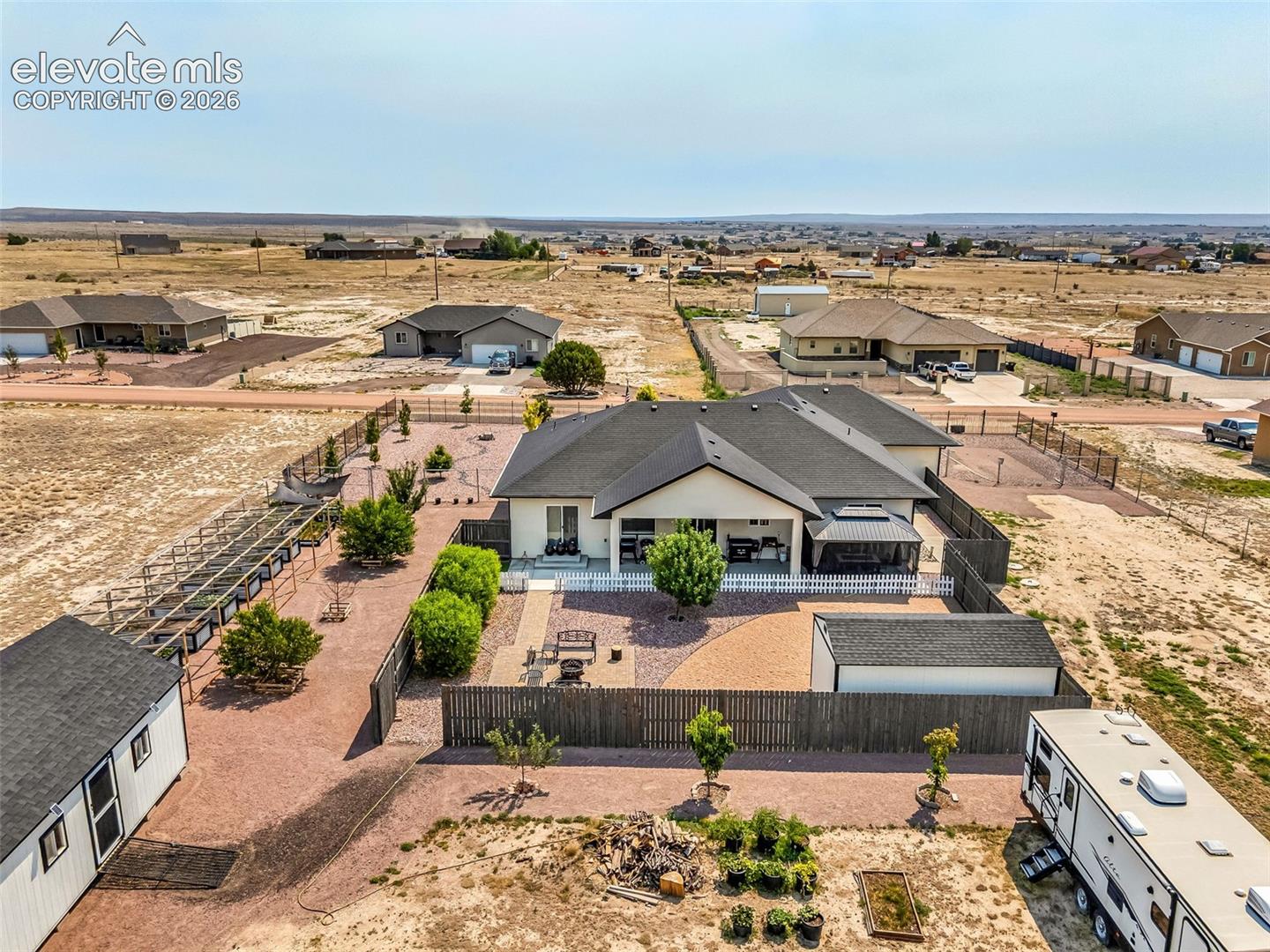 Expansive rear yard featuring a covered patio, a detached gazebo, and a fire pit area