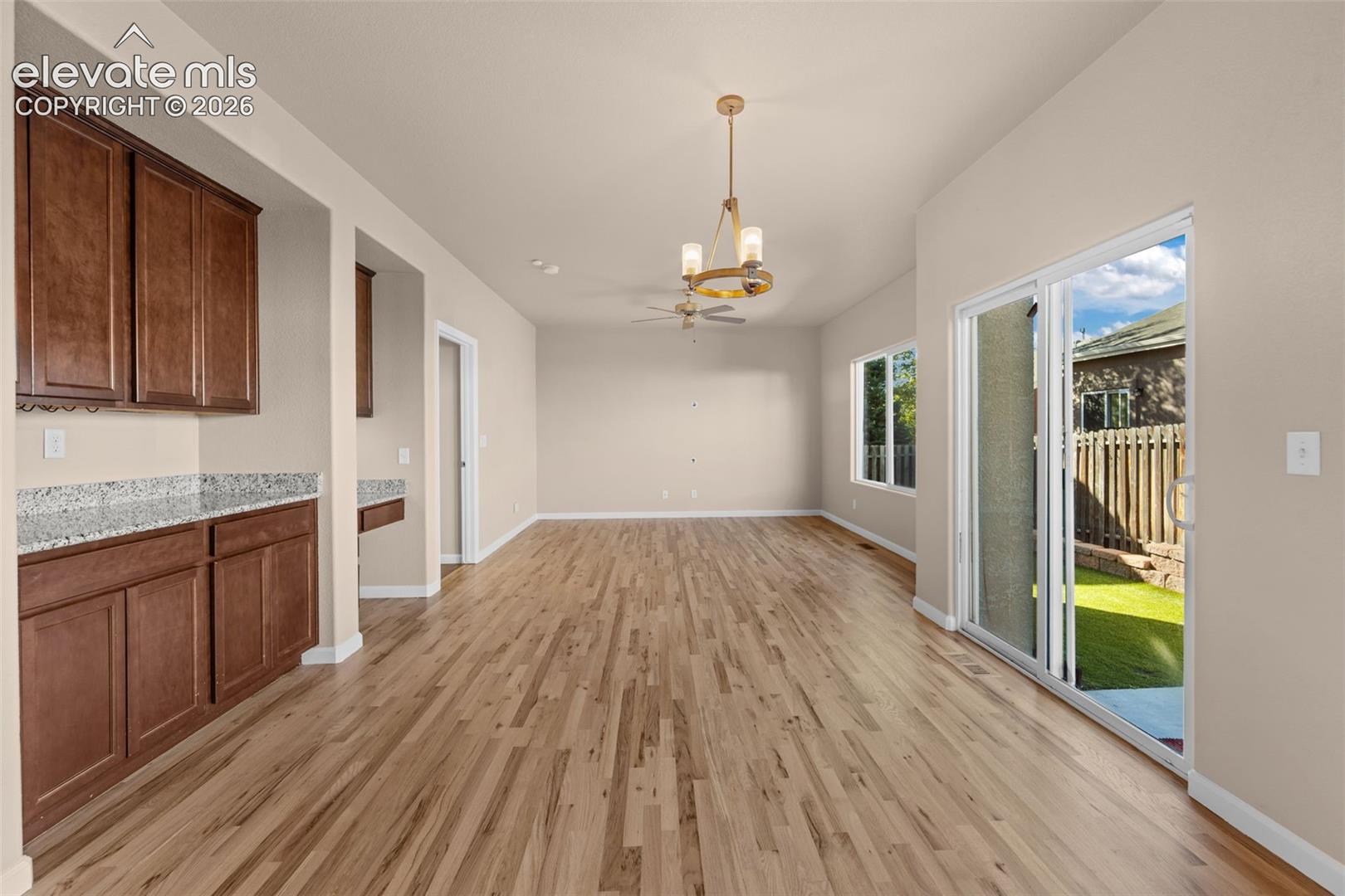 Open-concept interior featuring wood-finish flooring, built-in cabinetry with stone-finish countertops, a tiered chandelier, and sliding glass doors to the exterior
