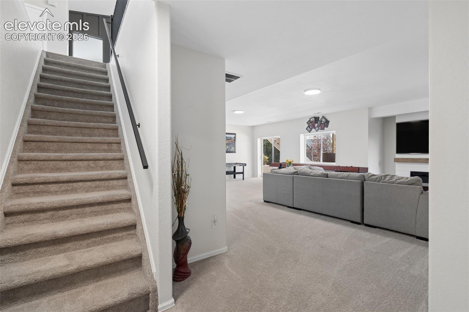 Carpeted staircase with a dark metal handrail