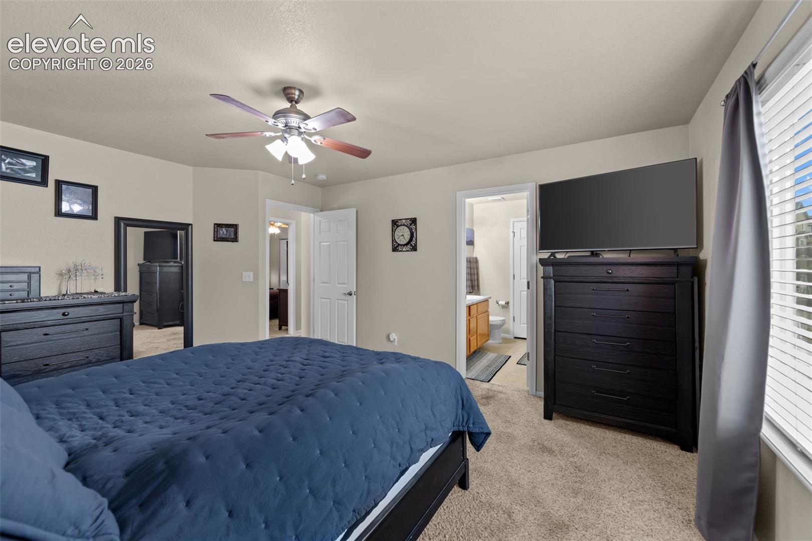 Carpeted flooring, ceiling fan with integrated lighting, window with blinds, and white interior doors