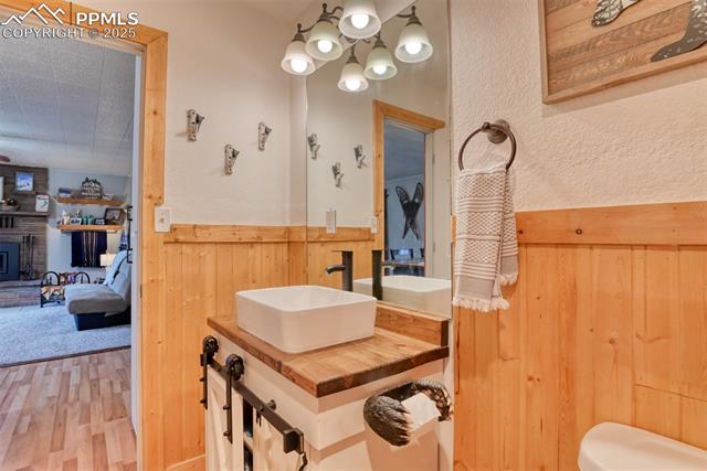Bathroom featuring wood walls, wood finished floors, vanity, a chandelier, and ensuite bathroom