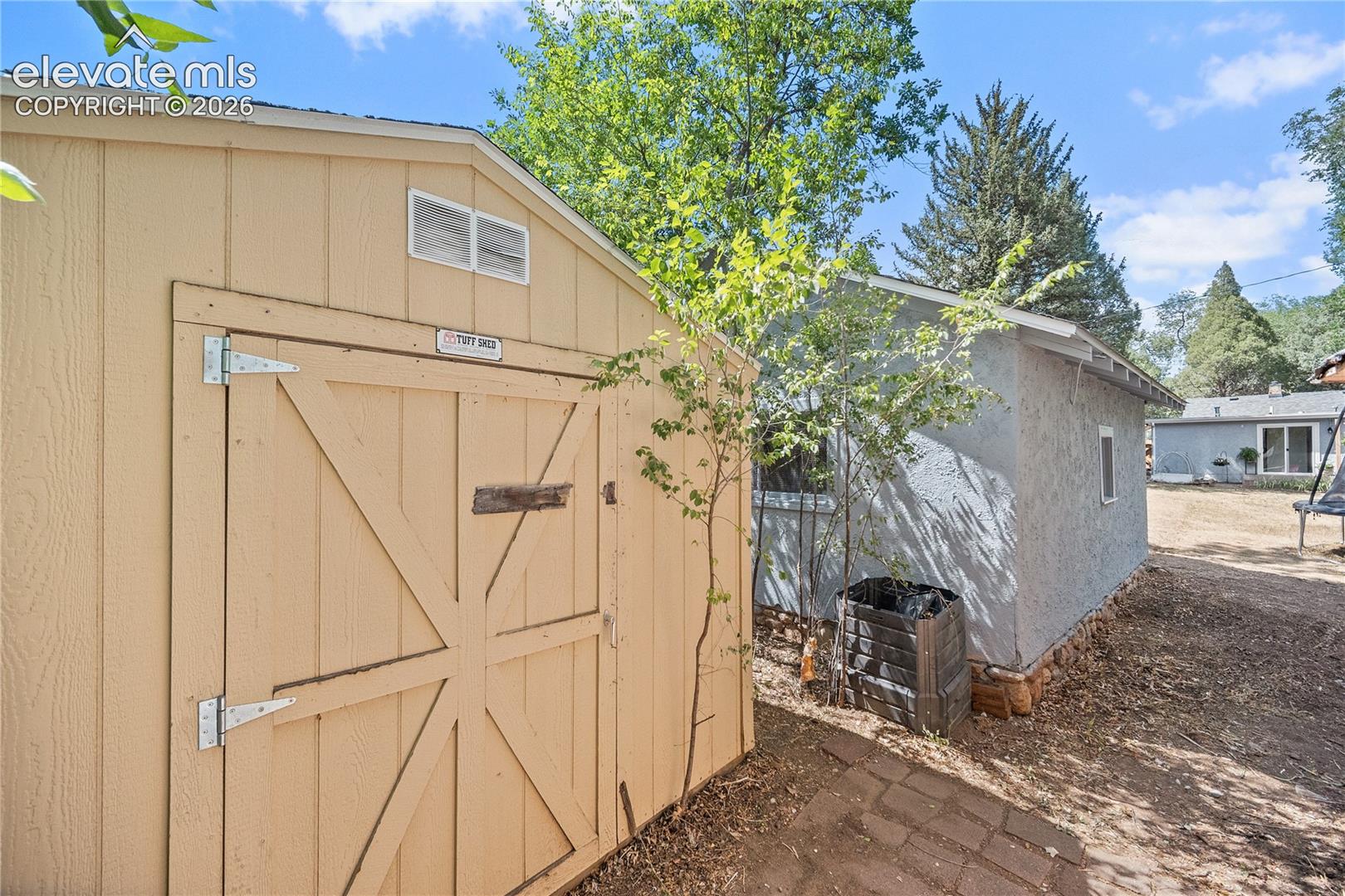 Light-toned storage shed with double doors and upper vents