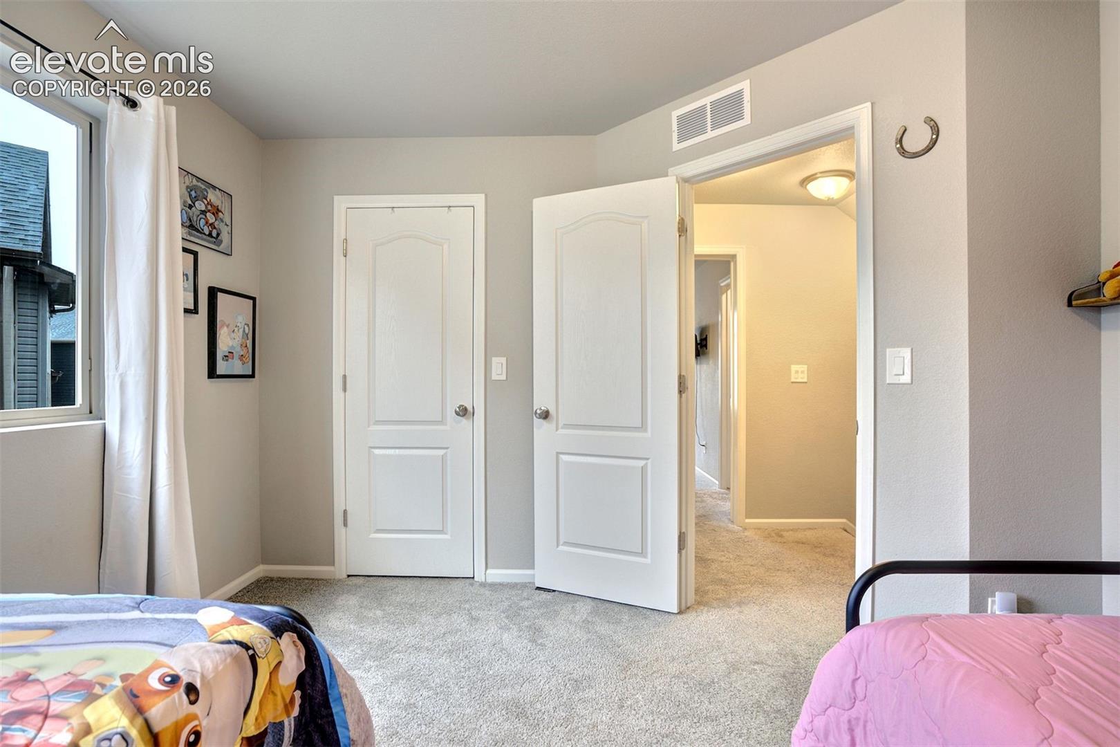 Neutral-toned room featuring neutral wall-to-wall carpeting, two white arched-panel doors, and a window with a large pane