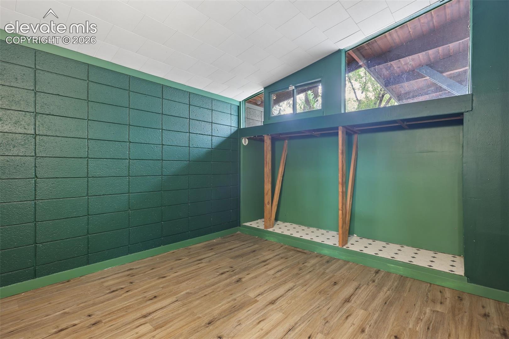 Wood-finish flooring with a green accent wall and a built-in elevated platform