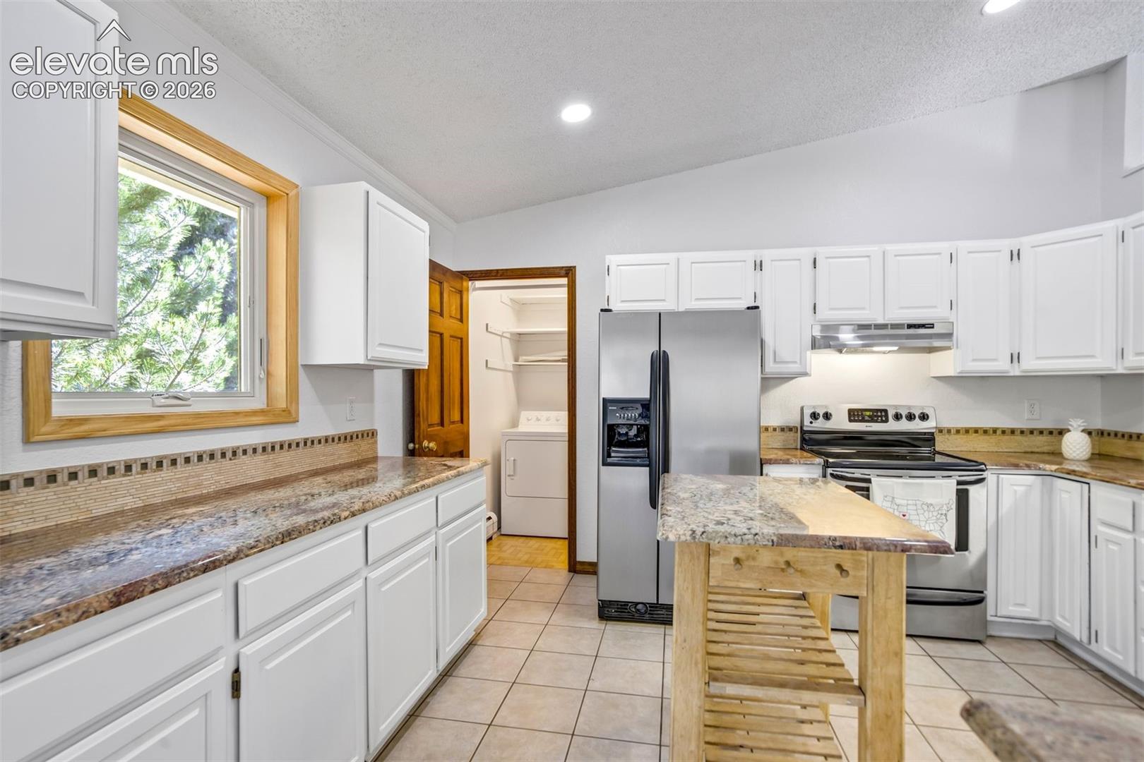 Kitchen featuring white shaker cabinetry, speckled countertops, stainless steel appliances, and tile flooring