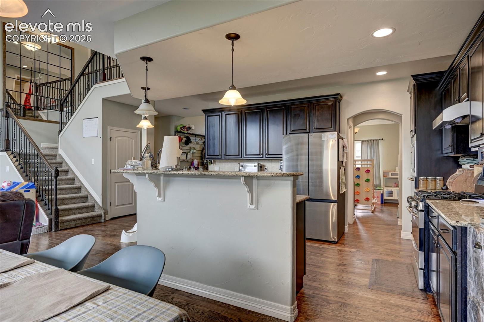 Kitchen with granite counters, island with breakfast bar and dark cabinetry