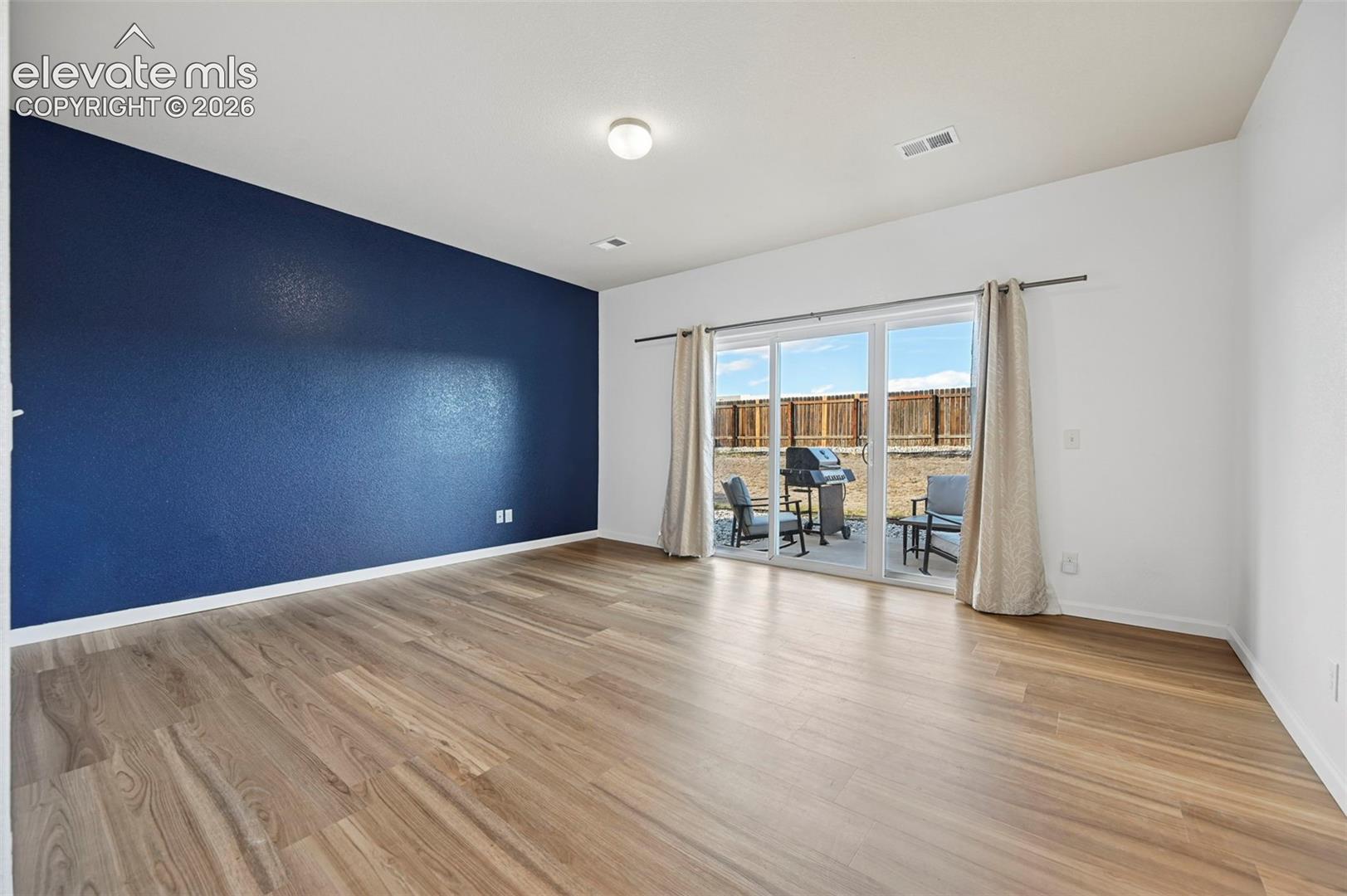 Living area featuring wood-finish flooring, a dark-toned accent wall, and sliding glass doors