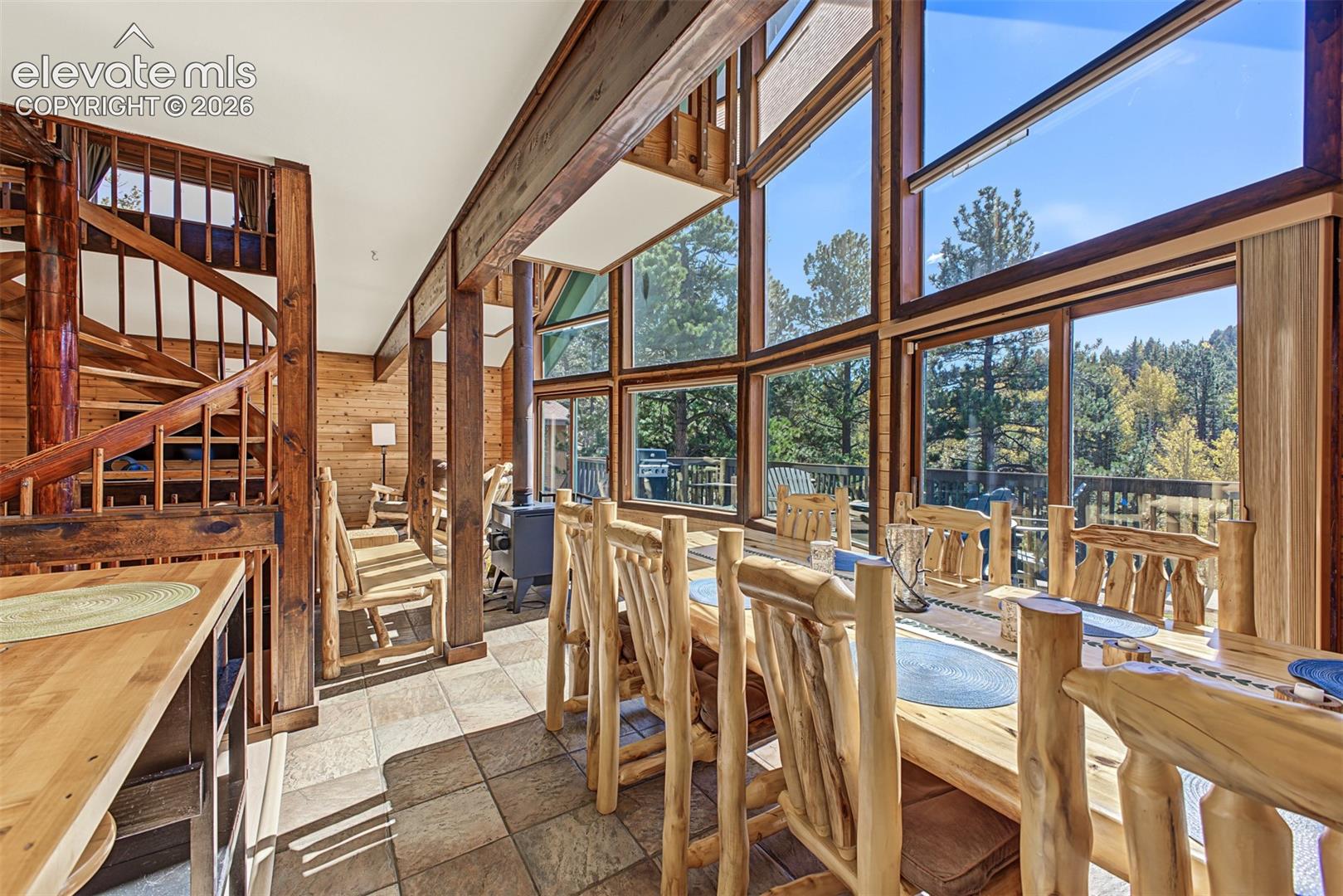 Expansive windows, spiral wood staircase, exposed wood beams, wood paneling, and tile flooring