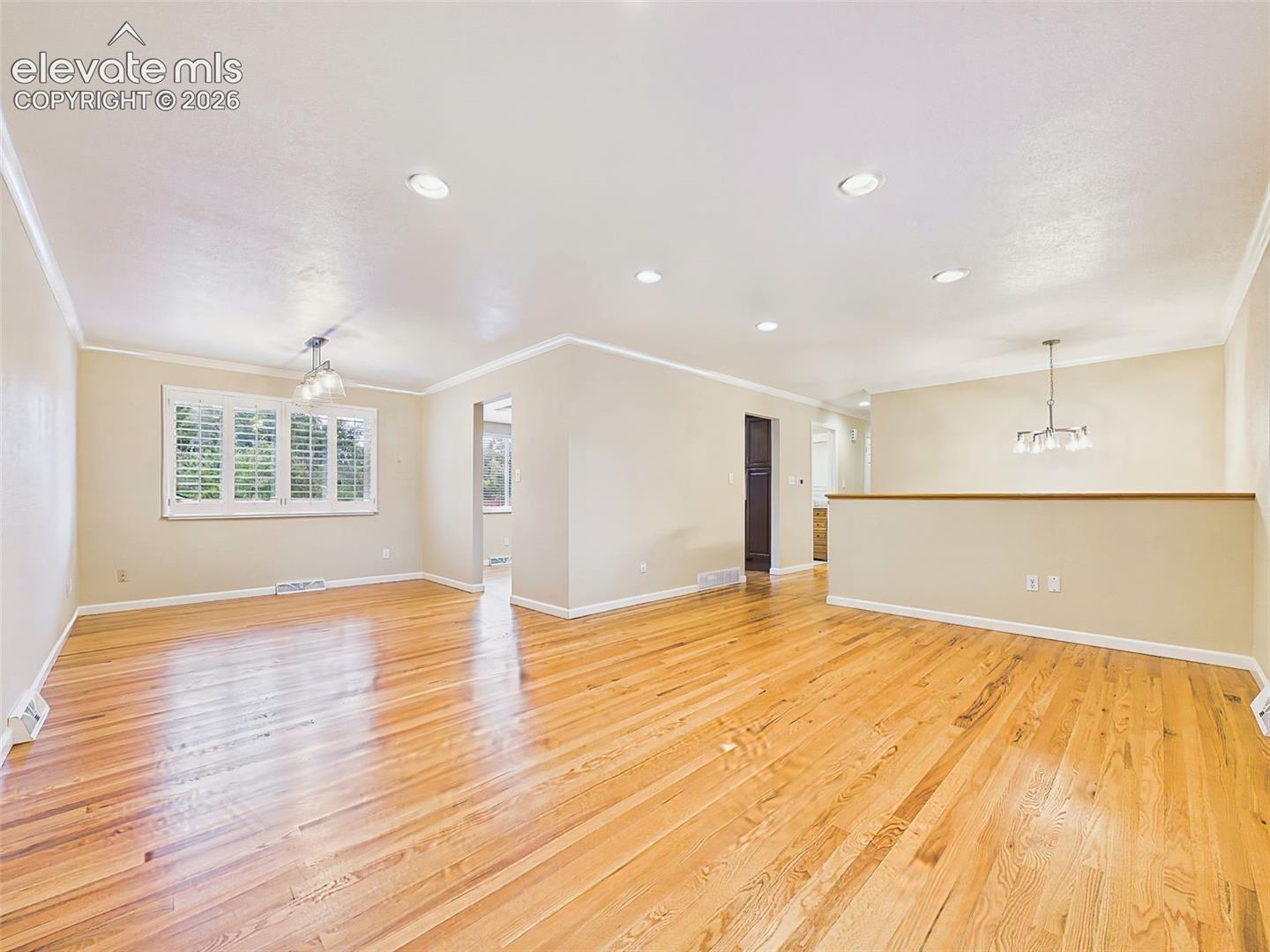 Living & Dining Areas – A wide view showcases the home's functional main-level layout, connecting the living room, dining area, and kitchen with warm hardwood flooring throughout.