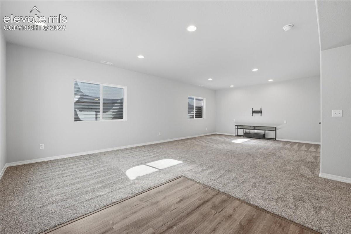 Neutral-toned interior space featuring recessed lighting, multi-textured flooring with carpeted and wood-finish surfaces, and two sliding windows